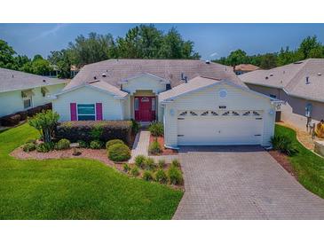 Charming single-story home with a well-manicured lawn, beautiful landscaping, and a brick-paved driveway at 1016 Eagles Lndg, Leesburg, FL 34748