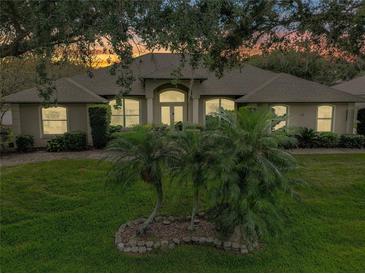 Charming single-story home featuring a well-manicured lawn and arched entryway, bathed in the warm glow of dusk at 11036 Bronson Rd, Clermont, FL 34711