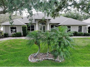 Charming home featuring lush landscaping and a well-manicured lawn with palm trees at 11036 Bronson Rd, Clermont, FL 34711