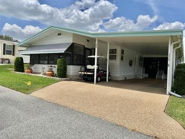 Charming home featuring a covered carport and well-maintained landscaping with vibrant green grass at 175 Hibiscus Way, Leesburg, FL 34748