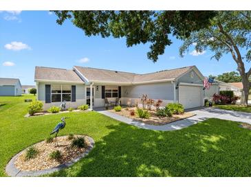 Charming single-story home featuring a well-manicured lawn, garden beds, and a welcoming front porch at 612 Lisbon Ln, The Villages, FL 32159