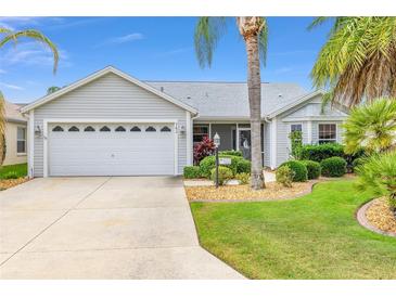 Charming single-story home featuring an attached two-car garage and lush landscaping with mature palm trees at 762 Turbeville Ter, The Villages, FL 32162
