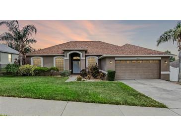 Charming single-story home featuring a well-manicured lawn, mature trees, and an attached two-car garage at 12838 Owasso Ln, Clermont, FL 34711