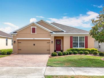 Charming single-story home with brick-paved driveway, manicured lawn, and a welcoming red front door at 1454 Westbury Dr, Clermont, FL 34711