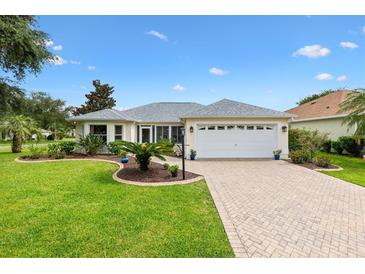 Charming single-story home with a well-manicured lawn, paver driveway, and a two-car garage at 1514 Vandam St, The Villages, FL 32162