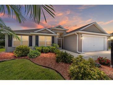 Charming single-story home featuring manicured landscaping, a two-car garage, and a welcoming entrance at 1910 Quiet Oak Ct, The Villages, FL 32162