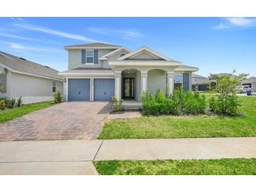 Charming home featuring a well-manicured lawn, an attached two-car garage, and a welcoming front porch with decorative pillars at 2025 Axel St, Minneola, FL 34715