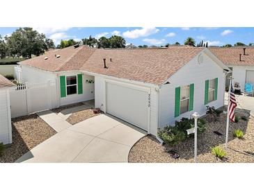 Charming single-story home featuring white siding, a brown roof, green shutters, and a well-manicured lawn at 2050 Duval Ct, The Villages, FL 32162