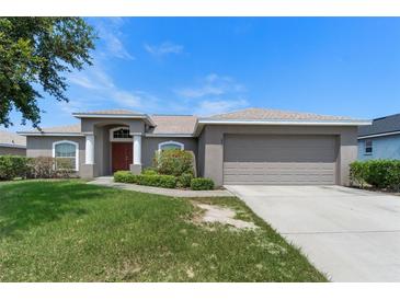 Charming single-story home with a well-maintained lawn and inviting front entrance with mature landscaping at 211 Highland Meadows Ct, Davenport, FL 33837