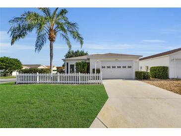 Charming home with a well-maintained lawn, picket fence, and a palm tree in a sunny neighborhood at 2111 Thornton Ter, The Villages, FL 32162