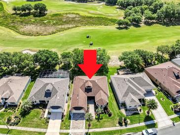 Aerial view of a single-Gathering home on a golf course with a mature landscaped yard and a screened-in pool at 3519 Arlington Ridge Blvd, Leesburg, FL 34748
