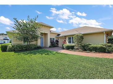 Inviting single-story home featuring lush landscaping, brick walkway, and a charming light yellow exterior at 39504 Hillrise Ln, Lady Lake, FL 32159