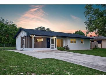 Charming single-story home features a screened-in porch, long driveway, and lush green lawn at 841 S Michigan Ave, Groveland, FL 34736