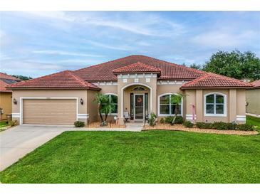 Charming single-story home with a well-manicured lawn, arched windows, and a beautiful red tile roof at 10240 Kabana Blvd, Clermont, FL 34711