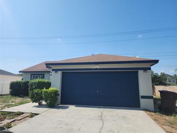Charming single-story home with blue garage door, landscaped front, and bright blue skies at 112 Arlington Ct, Haines City, FL 33844