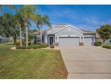Charming single-story home with a well-manicured lawn, stone accents, three-car garage, and beautiful landscaping at 11601 Thacker Dr, Clermont, FL 34711