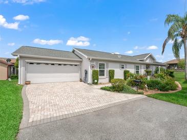 Charming single-story home with a two-car garage, brick driveway, and beautifully landscaped front yard at 17380 Se 111Th Ct, Summerfield, FL 34491