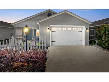 Charming gray home with a white garage door, white picket fence, and a cozy screened-in porch at 2142 Weber Ct, The Villages, FL 32163