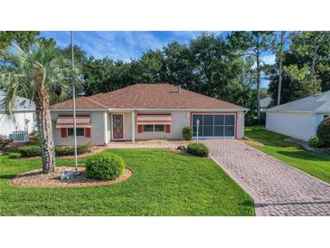 Charming home featuring a well-manicured lawn, brick driveway, and a cozy, inviting entrance at 2766 Privada Dr, The Villages, FL 32162