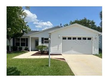 Charming one-story home featuring a two-car garage, well-maintained lawn, and attractive landscaping at 3337 Candlebrook St, The Villages, FL 32162