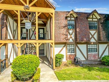 Charming condo with a Tudor-style exterior, lush landscaping, and covered entryway at 500 Newell Hill Rd # 113D, Leesburg, FL 34748
