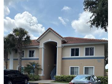A two-story building with a tile roof and tan exterior features a welcoming entrance and mature landscaping at 508 Villa Del Sol Cir # 105, Orlando, FL 32824