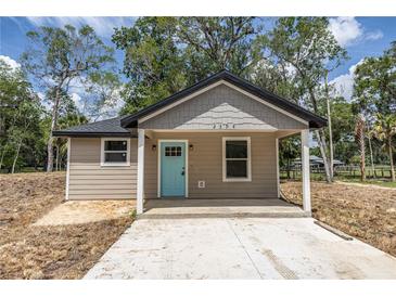 Charming single-story home features a stylish exterior with a blue front door and a well-lit porch area at Lot 21 Indian Estates Cr 423, Lake Panasoffkee, FL 33538
