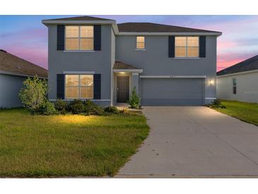 Charming two-story home features a well-maintained lawn, gray exterior, and attached two-car garage at 4713 Sw 86 Ln, Ocala, FL 34476