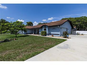Charming single-story home with a well-maintained lawn, blue exterior and a spacious driveway at 5521 Oak St, Mount Dora, FL 32757