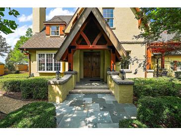 Inviting front entrance with a peaked portico, double wooden doors, and stone walkway, surrounded by lush greenery at 707 S Dixie Dr, Howey In The Hills, FL 34737