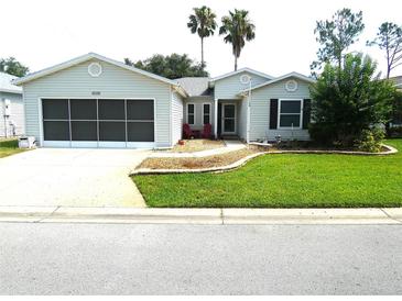 Charming single-story home with well-manicured lawn, gray siding and a screened garage door at 751 Old Oaks Ln, Leesburg, FL 34748