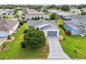 Beautiful single-story home with a well-maintained lawn, gray driveway, and a screened-in pool at 8039 Se 174Th Belhaven Loop, The Villages, FL 32162