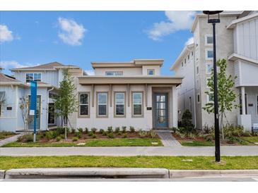 Charming modern home featuring a stylish blue front door, complemented by manicured landscaping at 9674 Rodbell St, Orlando, FL 32827