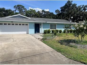 Charming single-story home with a blue exterior, attached garage, and well-maintained front lawn at 11812 Watts Ct, Tavares, FL 32778