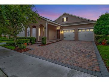 Charming single-Gathering home boasts an arched entryway and a two-car garage with a brick paver driveway at 15531 Waterleigh Cove Dr, Winter Garden, FL 34787