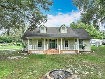 Charming home with a welcoming front porch, dormer windows, and a well-maintained lawn with mature shade trees at 17670 Se 283Rd Ave, Umatilla, FL 32784