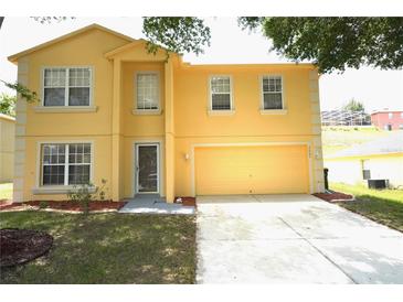 Two-story yellow home featuring an attached garage and well-maintained lawn at 2007 Country Brook Ave, Clermont, FL 34711