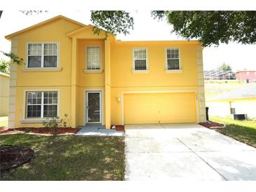 Two-story yellow home with an attached garage, well-maintained lawn and mature trees at 2007 Country Brook Ave, Clermont, FL 34711