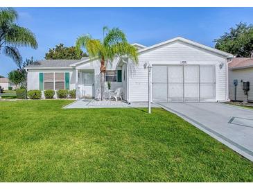 Charming single-story home with well-manicured lawn, white siding, and a decorative palm tree in the front yard at 2799 Privada Dr, The Villages, FL 32162