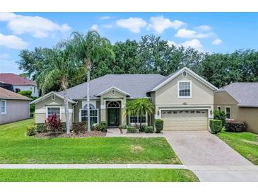 Charming single-story home featuring lush landscaping, mature palm trees, and a welcoming two-car garage at 4239 Fawn Meadows Cir, Clermont, FL 34711