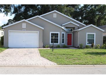 Charming single Gathering home featuring a well-manicured lawn, brick driveway, and a vibrant red front door at 5436 Astor St, Leesburg, FL 34748