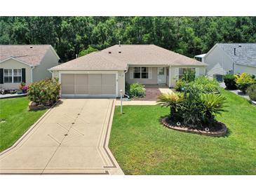 Charming single-story home featuring a well-manicured lawn and a beautifully patterned driveway at 8377 Se 177Th Bartram Loop, The Villages, FL 32162