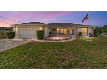 Charming single-story home featuring a well-manicured lawn, a two-car garage, and a welcoming screened-in porch at 8850 Se 156Th St, Summerfield, FL 34491