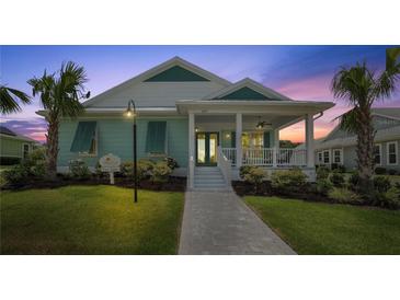 Charming coastal-style home featuring a welcoming front porch, lush landscaping, and a well-manicured lawn at 1057 Sugarloaf Key Loop, Lady Lake, FL 32159