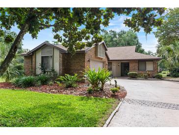 Charming brick home with well-manicured landscaping, green lawn, and a spacious driveway at 112 Waterwood Dr, Yalaha, FL 34797