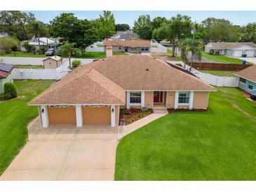 Charming single-story home featuring a two-car garage, manicured lawn, and lovely landscaping at 1414 Cove Pl, Tavares, FL 32778