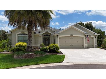 Charming home featuring a three-car garage, landscaped front yard, and elegant architectural details at 1553 Lynchburg Loop, The Villages, FL 32162