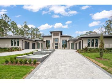 Stunning modern home featuring a beautiful paver driveway and a decorative water feature in a landscaped front yard at 16320 Pendio Dr, Bella Collina, FL 34756