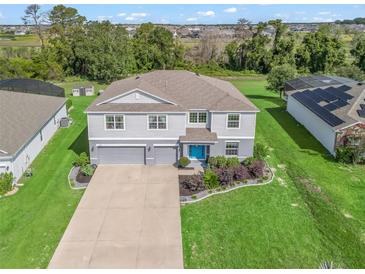Beautiful two-story home with well-manicured lawn and a three car garage and a bright blue front door at 1824 Forest Glen Dr, Fruitland Park, FL 34731