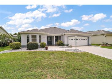 Charming one-story home with a well-manicured lawn, stone accents, and an attached two-car garage at 2104 Gerardo Ave, The Villages, FL 32159